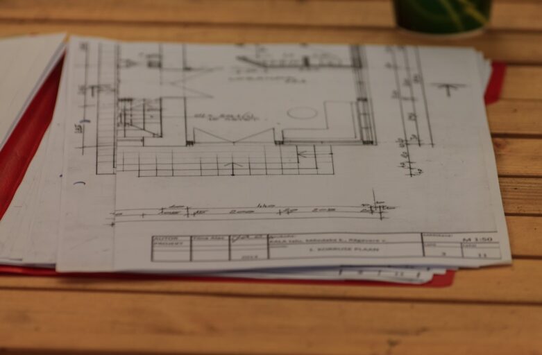 Architect's hands sketching detailed plans for a modern home on a bright, clean drafting table with professional tools.
