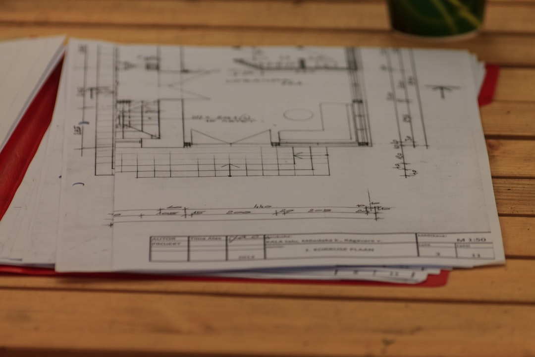 Architect's hands sketching detailed plans for a modern home on a bright, clean drafting table with professional tools.