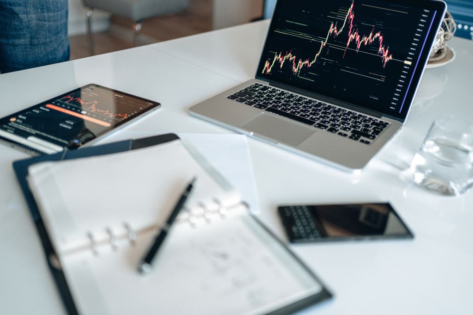 A clean, modern desk setup with a tablet displaying colorful map data and analytics next to a laptop and a cup of coffee, representing a modern marketer's toolkit.