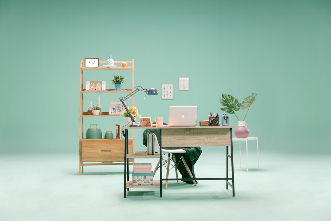 A marketer and a developer working together at a bright, modern office desk, pointing at a single laptop screen to bridge the gap between their departments.